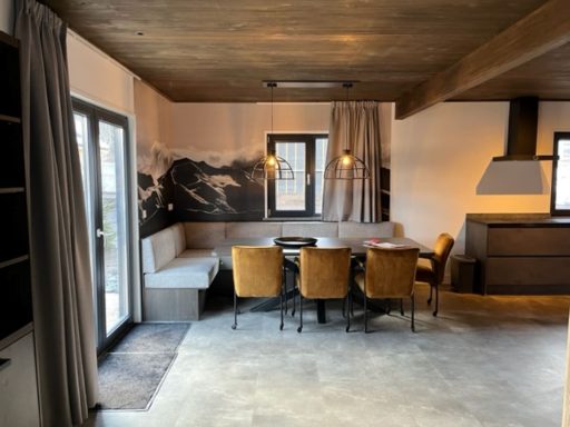 Hedendaagse eetkamer met een grote tafel, stoelen en een gezellige zithoek.