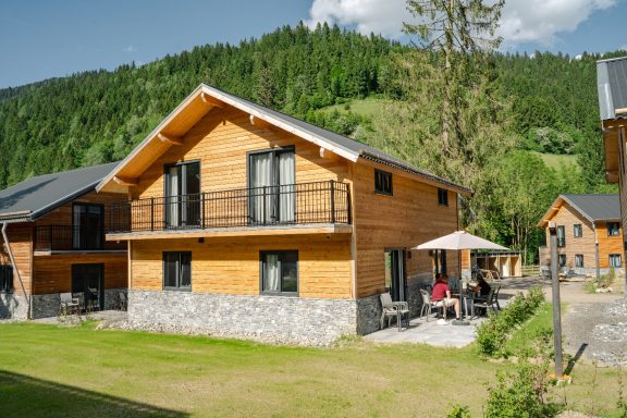 Moderne houten vakantiewoning met terras in een groene omgeving.